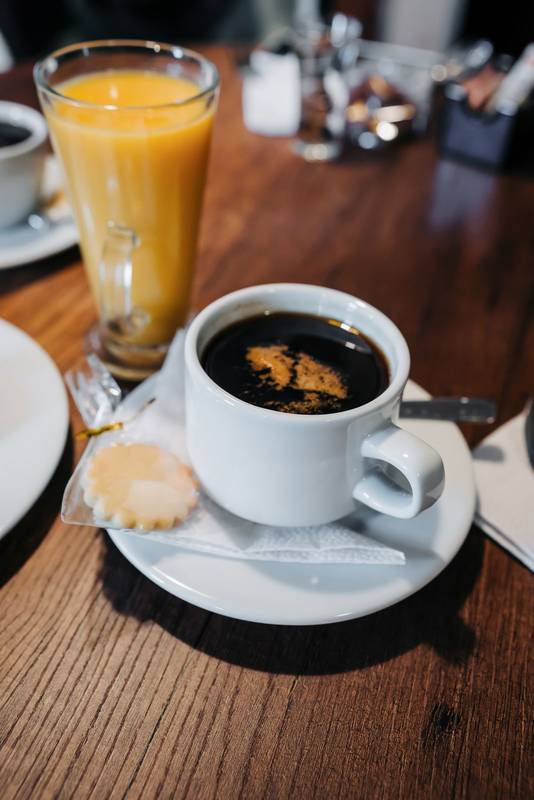 coffee with cream and orange juice on wooden table, hot caffeinated drink as breakfast