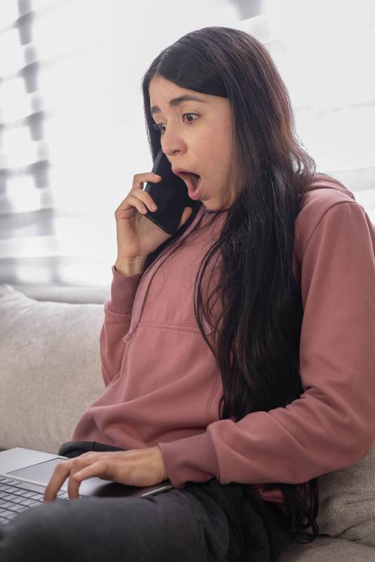 staring at her smartphone with a surprised expression after seeing unexpected news online.