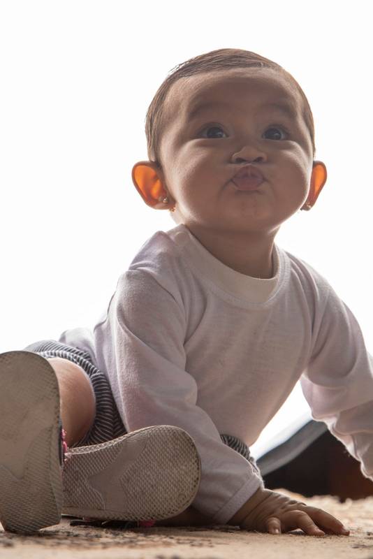 baby making gestures with her face, wearing casual clothes in a studio, sending a kiss