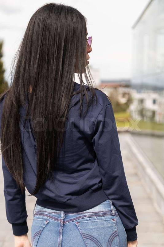 woman with long, straight black hair posing on her back and standing in a casual jacket