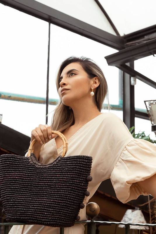 standing holding a knitted purse latin young woman with long hair wears formal and fashionable clothes