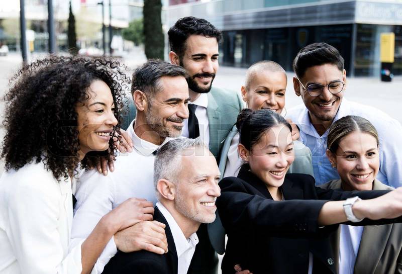 Multiracial group of successful business people taking a selfie outside. Diverse office colleagues taking a picture together smiling and bonding in the street.