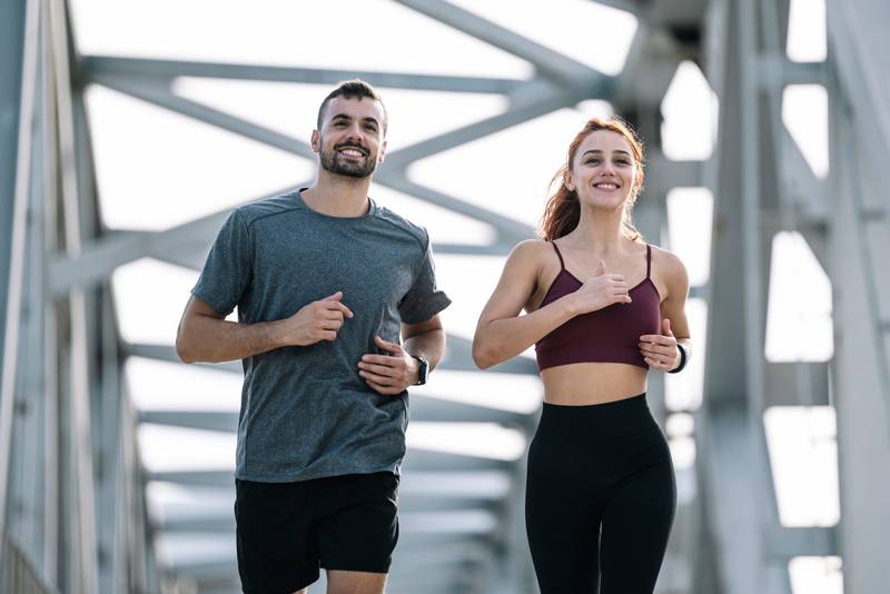 Happy athletic couple having fun while running outside. Adult sport man and woman friends training together.