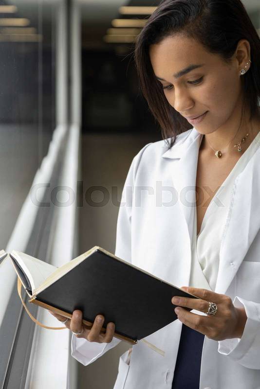 female doctor reading a book, wearing a white coat, professional