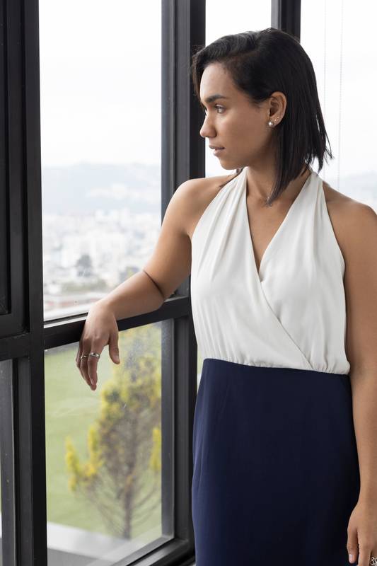 young latin woman with short hair, leaning against a metal railing
