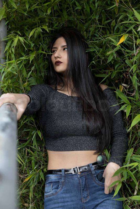 slim young latin woman wearing casual and modern clothes, in the background several leaves