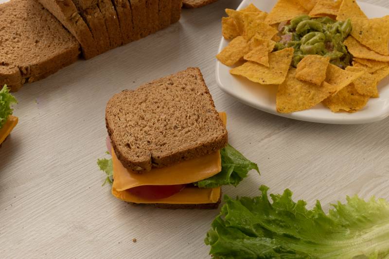 bread, cheese, lettuce and a plate with nachos on a table, delicious prepared food, snack