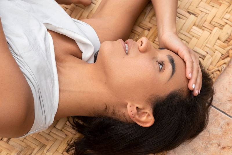 woman with black hair, worried lying down resting with headache