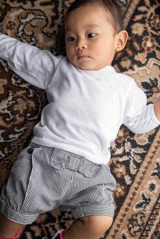 cute and adorable toddler lying on a textured rug in a studio