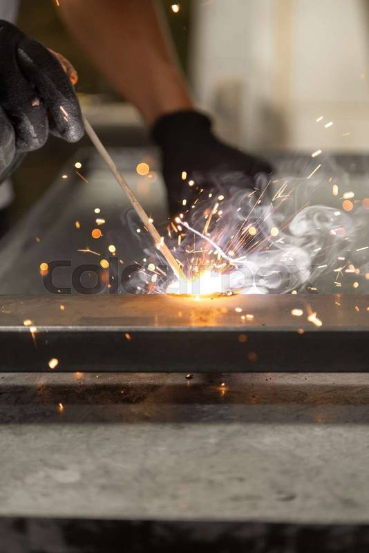 hands of a person wearing black protective gloves while using a metal welding tool