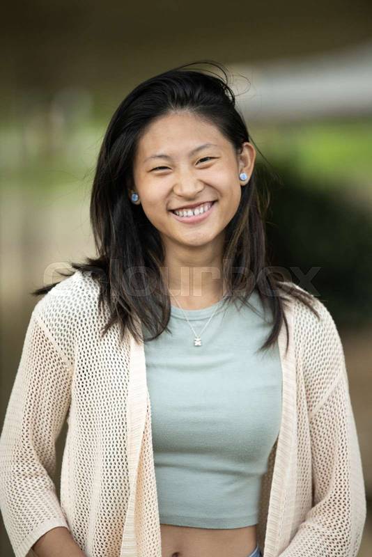 Beautiful cheerful young lady looking at camera standing outside.Joyful happy woman laughing staring at camera in the street.
