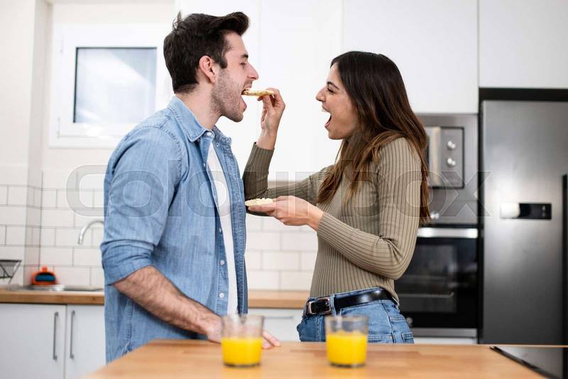 Happy young couple preparing healthy food on the kitchen. Romantic and funny breakfast