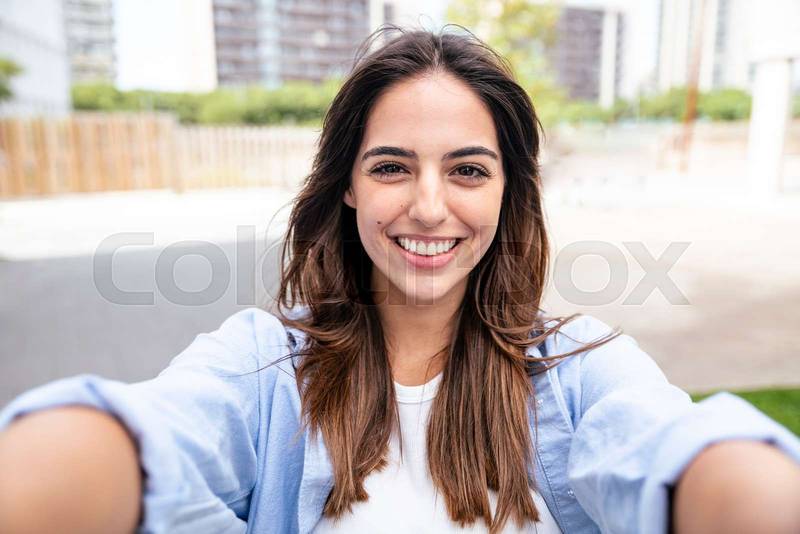 Beautiful young woman taking selfie in the city