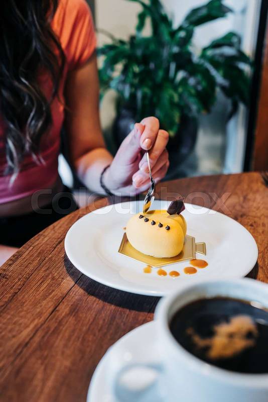 gourmet dessert decorated with icing, person's hand holding spoon and eating