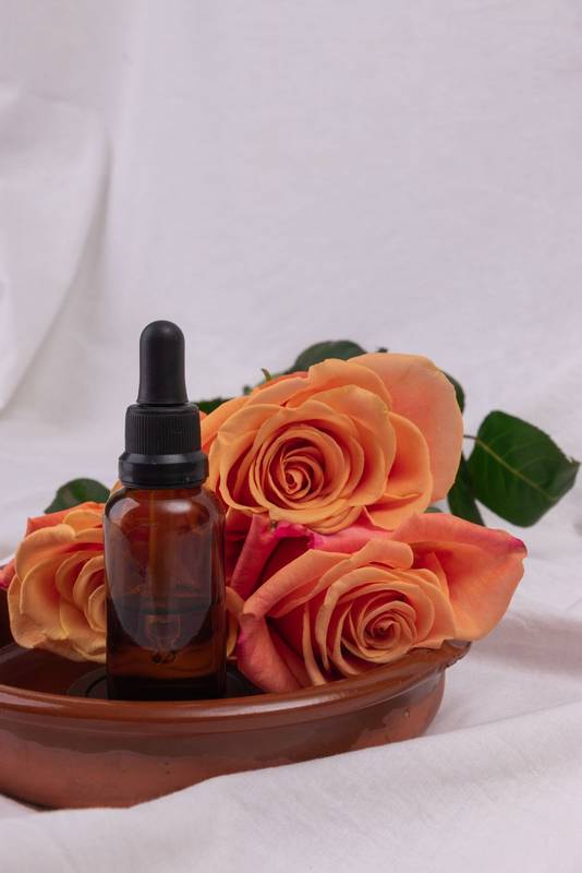 oil extract in a bowl next to roses, natural cosmetic product, object