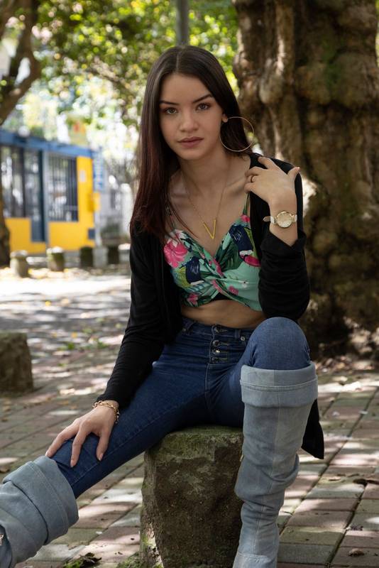 woman sitting on a stone, wearing jewelry, semi-formal dress
