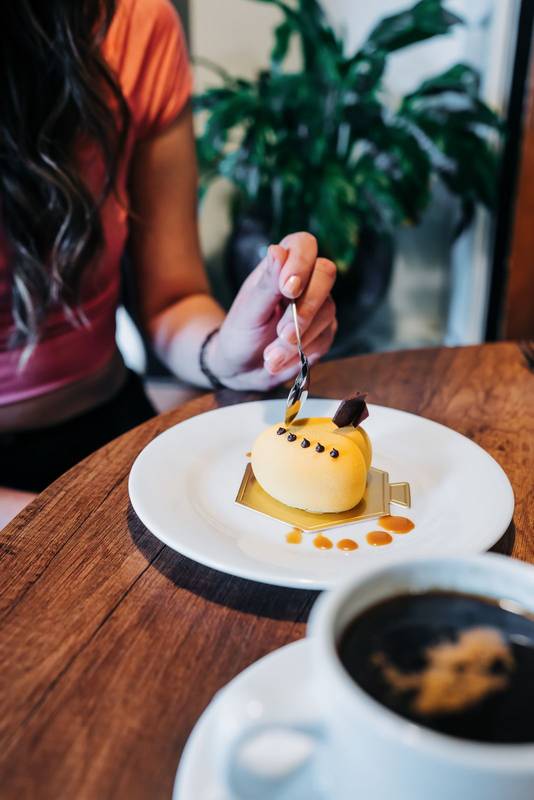 gourmet dessert decorated with icing, person's hand holding spoon and eating