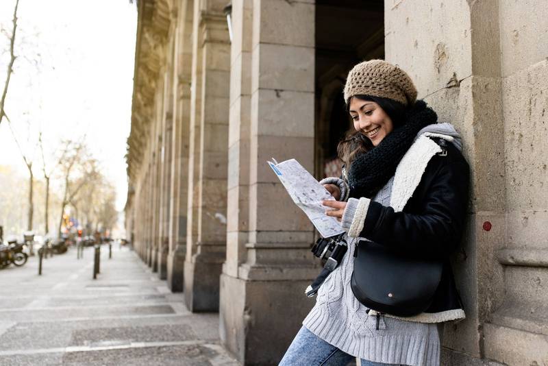 young tourist woman exploring city map in the street. holidays, tourism and travel concept
