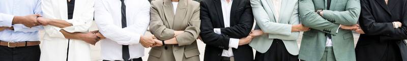 Panoramic close up of an executive team standing in a line holding hands. Businesspeople bonding together standing. Teamwork concept