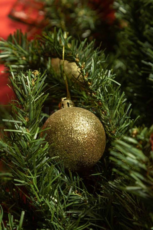 branch of an artificial pine decorated with a golden and frosted light bulb