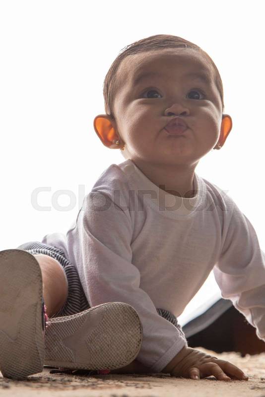 baby making gestures with her face, wearing casual clothes in a studio, sending a kiss