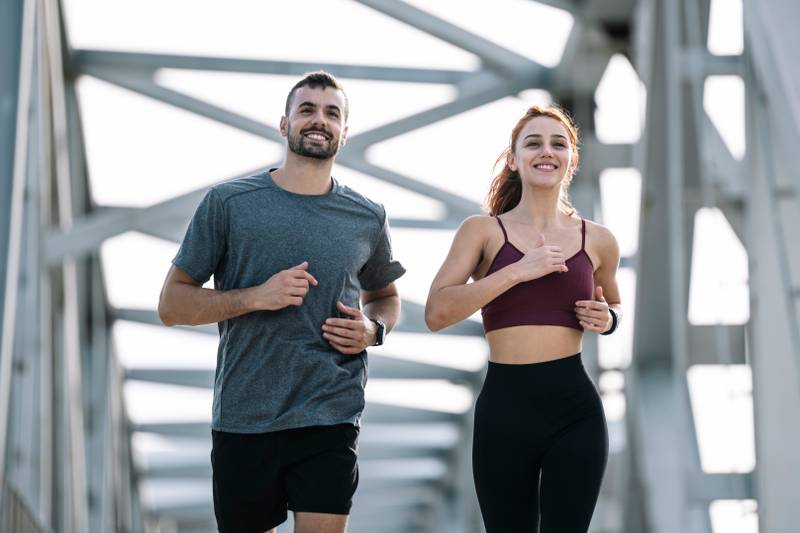Happy athletic couple having fun while running outside. Adult sport man and woman friends training together.