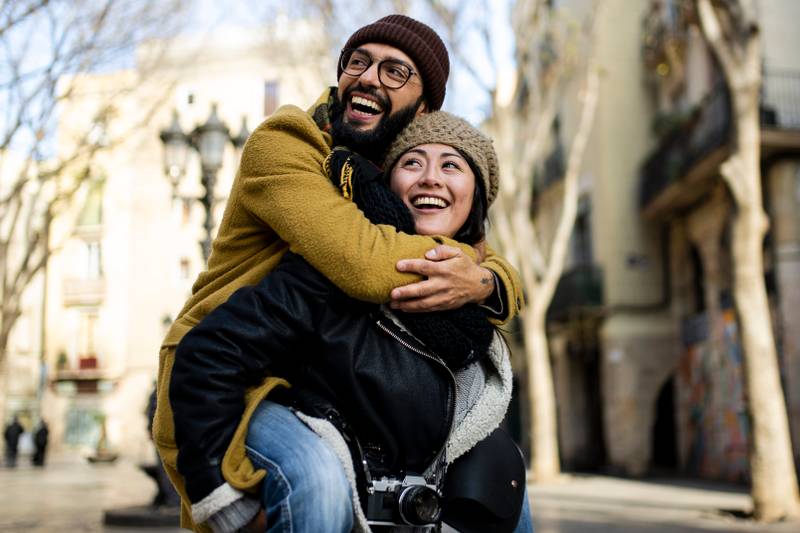 Couple of tourists having fun walking on city street at holiday - Happy friends laughing together on vacation - People and holidays concept