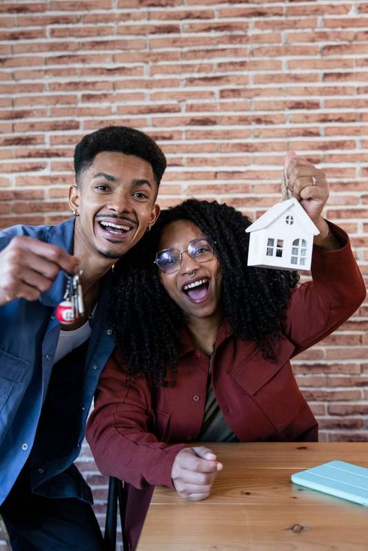 Joyful couple celebrating buying new home showing keys and looking at camera. Happy man and woman smiling and holding keys of their property.