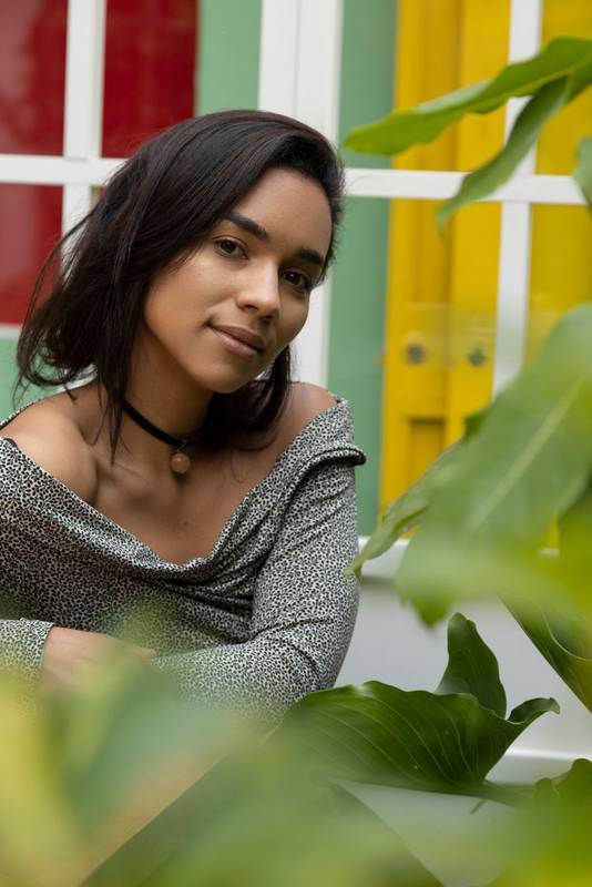 girl smiling while standing behind a plant