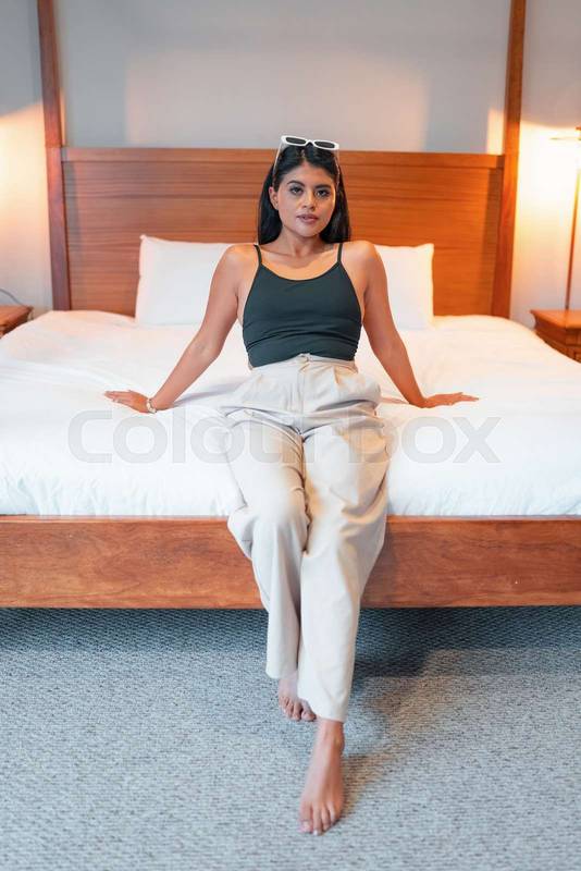 comfortable bed in the interior of the room a young woman with black hair and light clothes, model lifestyle