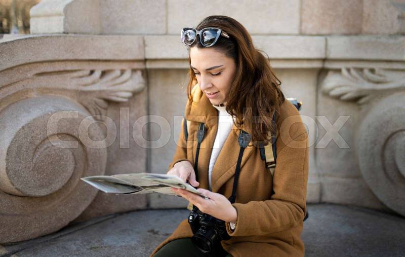 happy traveller woman looking a map outdoors. cheerful young female on vacations.