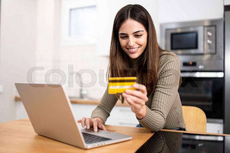 happy young attractive woman shopping online with a laptop computer using a credit card. e-commerce, business concept