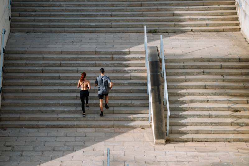 Sportive couple during workout stair running outside. Fitness active lifestyle athletic people exercising cardio climbing staircase.