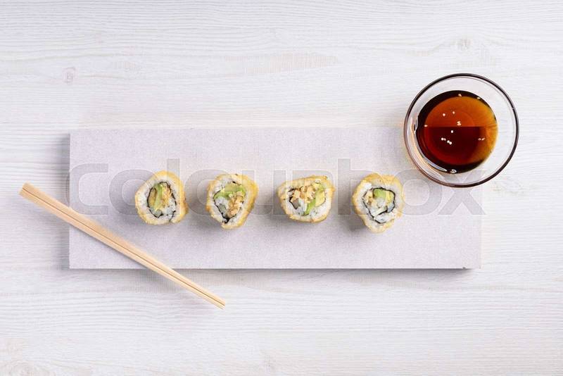 plate with sushi rolls, container of soy sauce and some wooden chopsticks, food in studio, delicious