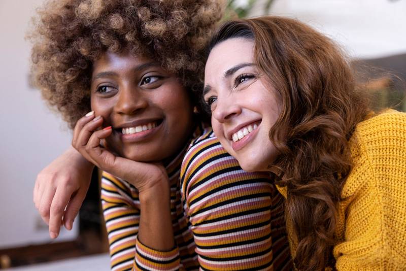 Close up of a beautiful multiracial couple hugging and relaxing. Portrait of two multiethnic smiling young women cuddling.