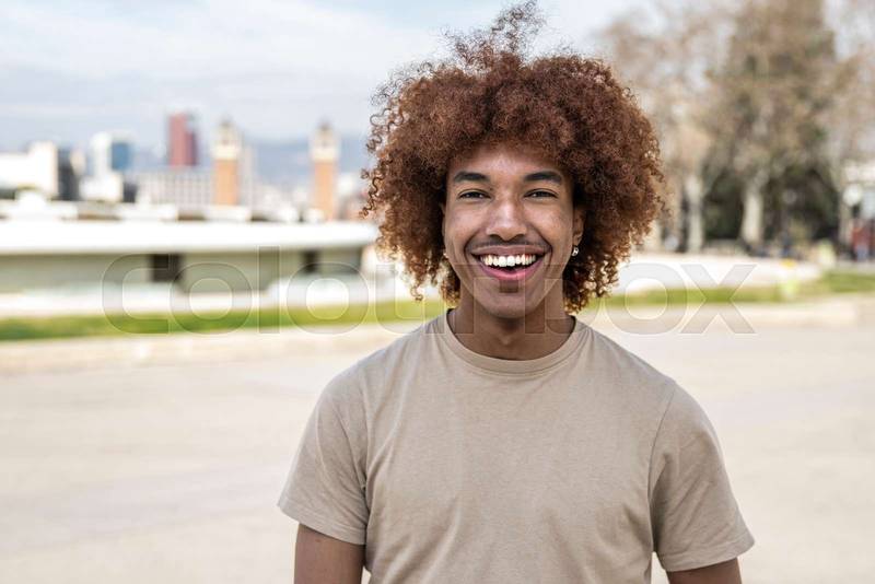 Young handsome guy smiling relaxed and looking at camera in the street. Confident happy man laughing and staring at camera standing outdoors.