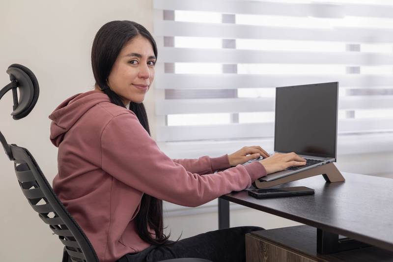 professional woman sits at her office desk, typing on a laptop, concentrating on her work, showcasing focus and productivity