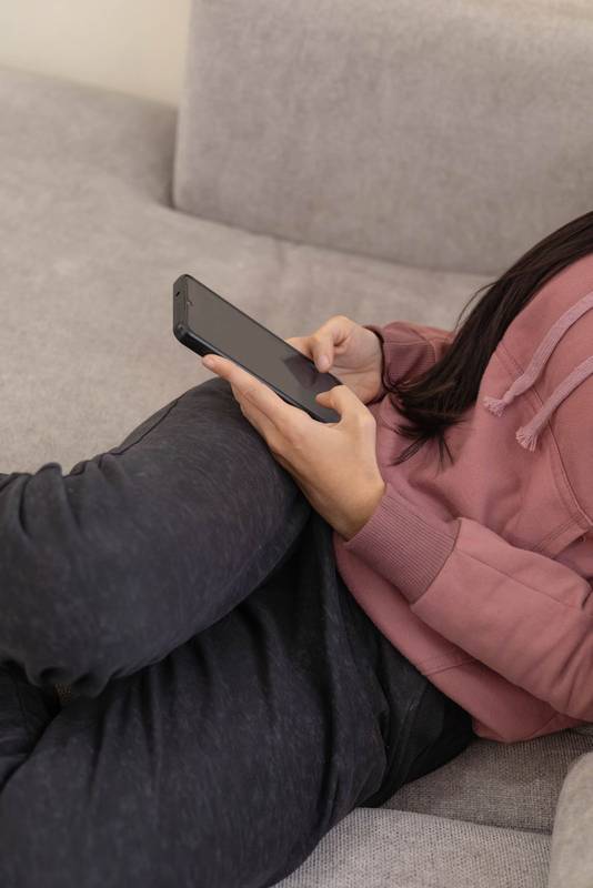 focused on texting on her smartphone in a cozy and bright home interior.