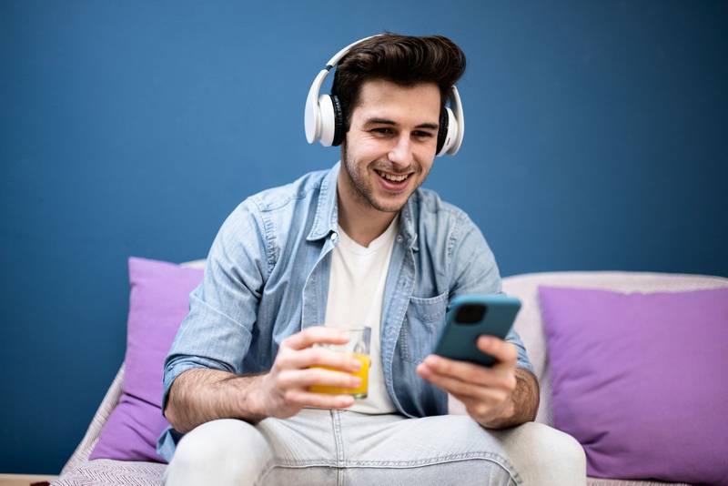 Man sitting in front of the computer holding a credit card at home - Young adult doing a online payment with his laptop at kitchen - business, technology concept