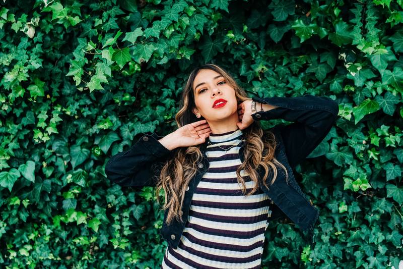 latin young female model with long blonde hair, wear makeup, red lips, casual striped dress and jacket, lifestyle