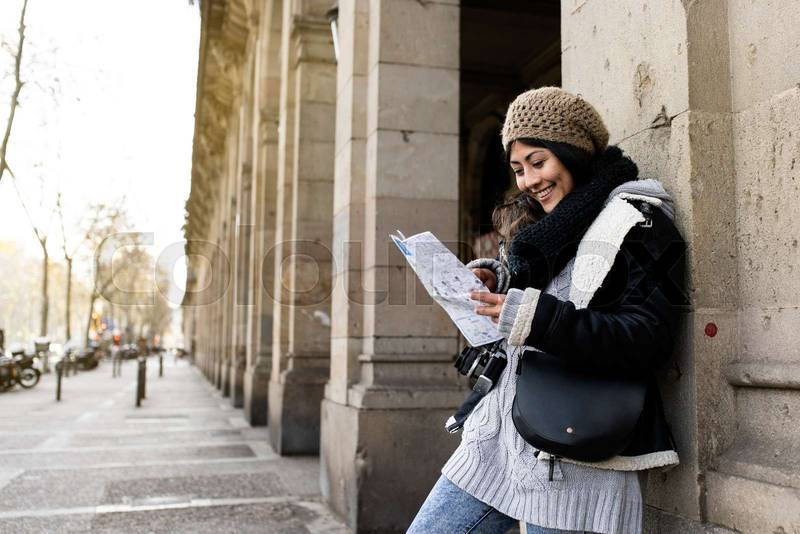 young tourist woman exploring city map in the street. holidays, tourism and travel concept