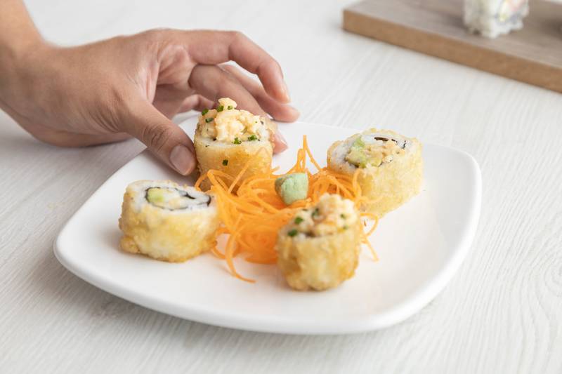 hand decorating a plate with sushi rolls, sea food