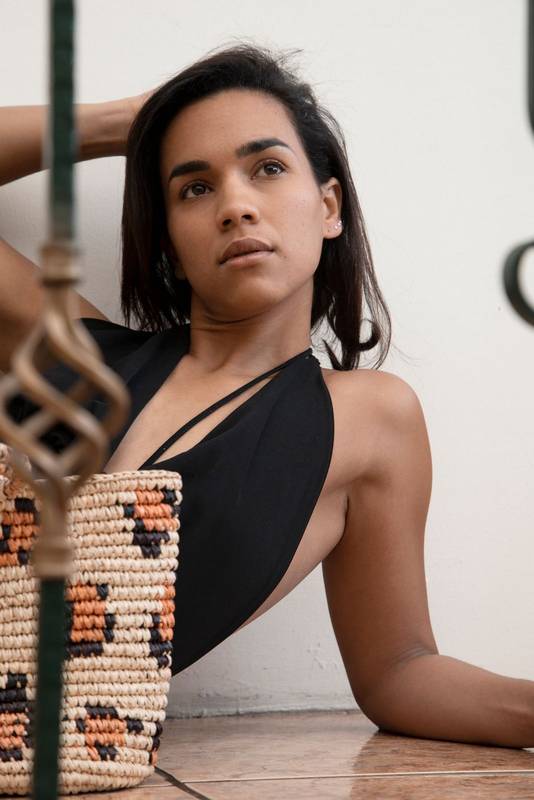 Latin young woman with natural makeup and short black hair, wears a black blouse, is posing in a sensual way
