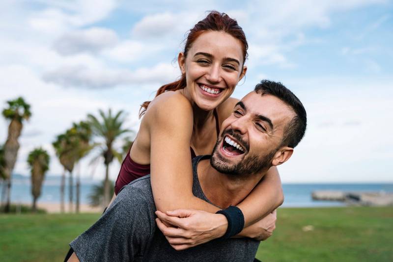 Lovely active athletic boyfriend and girlfriend hugging and having fun during a training. Affectionate young handsome happy fitness couple outside. 