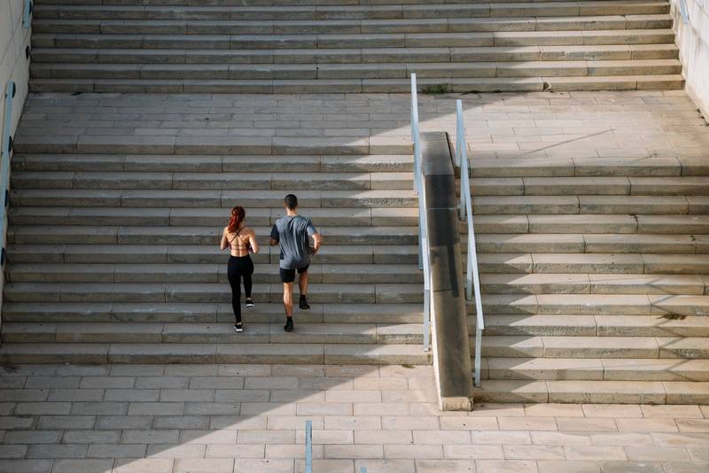 Sportive couple during workout stair running outside. Fitness active lifestyle athletic people exercising cardio climbing staircase.