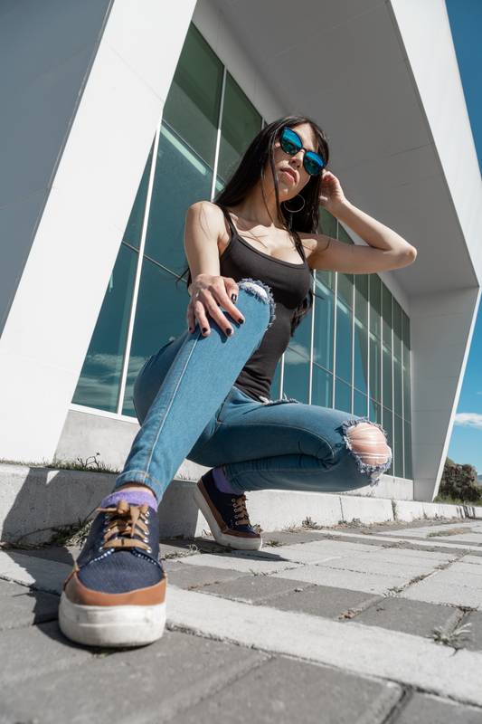 oman with long black hair smiling while wearing blouse, casual shoes and jeans, beauty