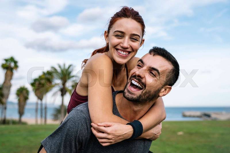Lovely active athletic boyfriend and girlfriend hugging and having fun during a training. Affectionate young handsome happy fitness couple outside. 