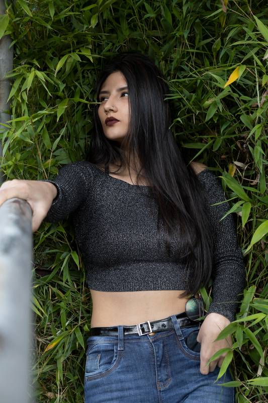 slim young latin woman wearing casual and modern clothes, in the background several leaves