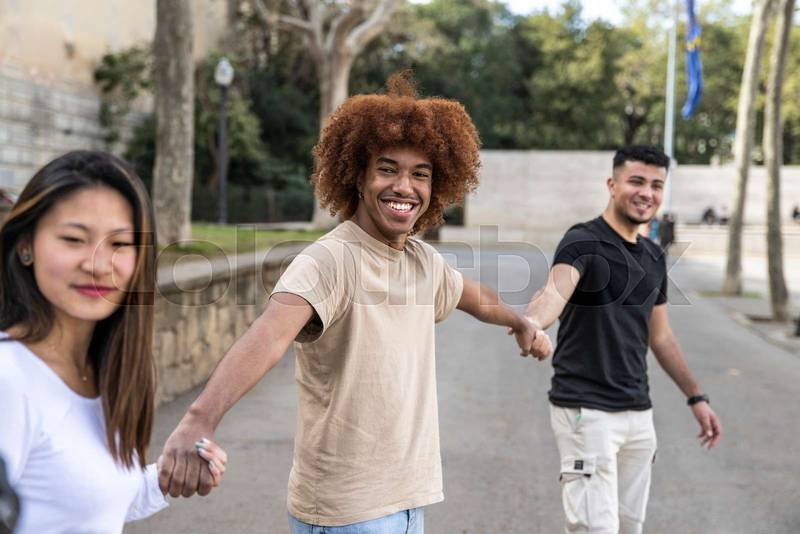 Three diverse and confident friends holding hands together. Multiracial group of people smiling and holding hands in a line.