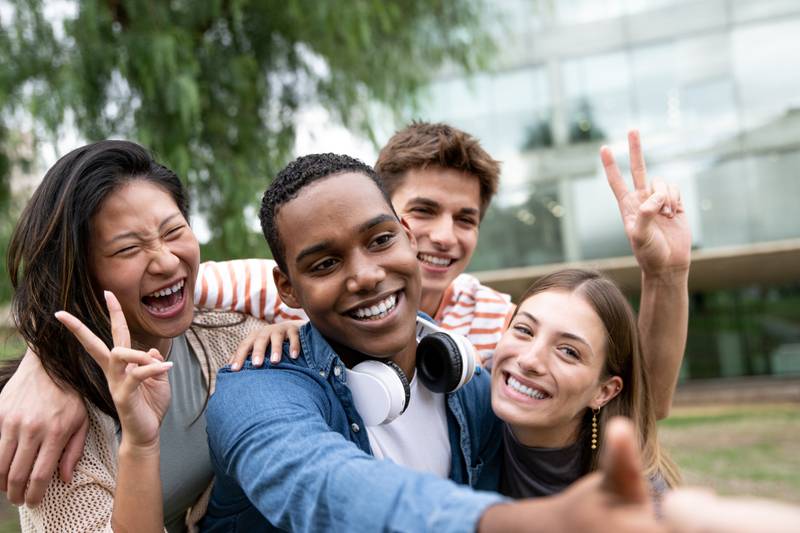 Cheerful group of friends taking a selfie laughing.Multiracial young people having fun and taking pictures outside.